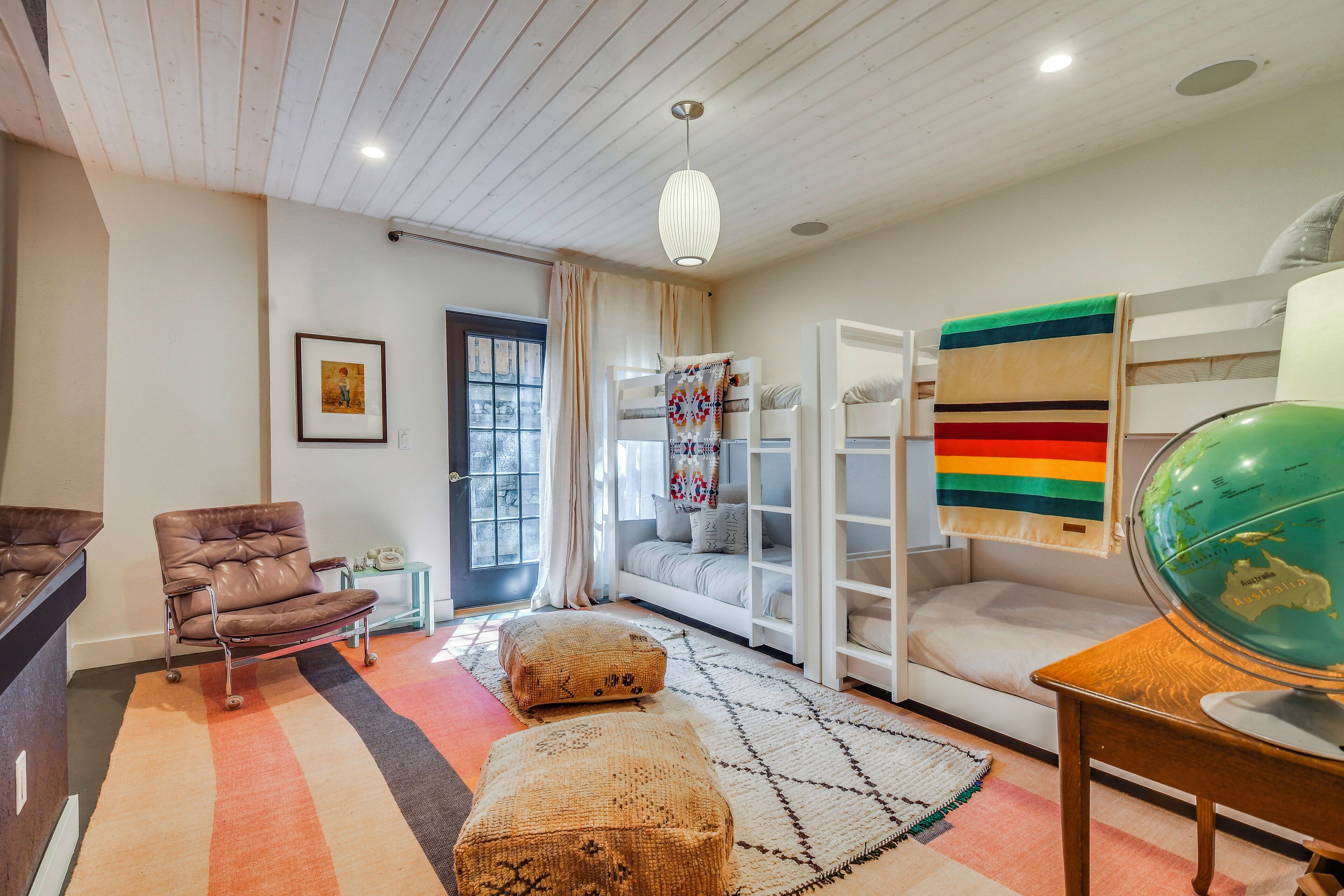 Une chambre avec un lit superposé, un globe terrestre, une chaise, un bureau et une fenêtre avec des rideaux.