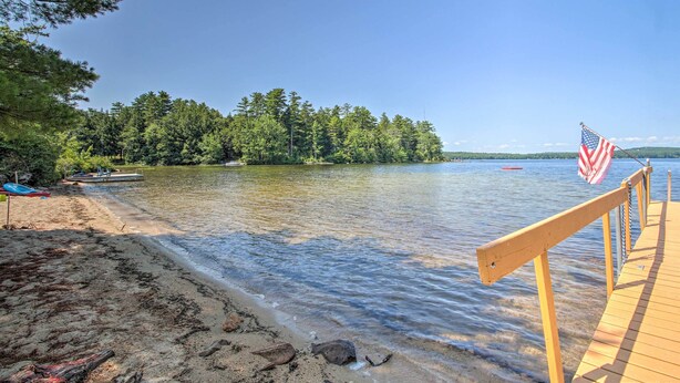 Eine Holzsteganlage, die sich in einen stillen See erstreckt, umgeben von dichtem Wald und einer amerikanischen Flagge.