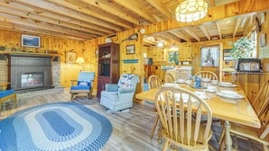 Ein Holzblockhaus-Interieur mit Essbereich, Kamin und Küche.