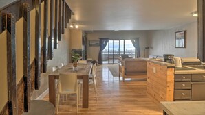A spacious kitchen with a wooden island, a dining area with a long table and chairs, and a staircase with exposed metal railings. - Whitefish Mountain Ski-in/out Condo w/ Views! (Whitefish)