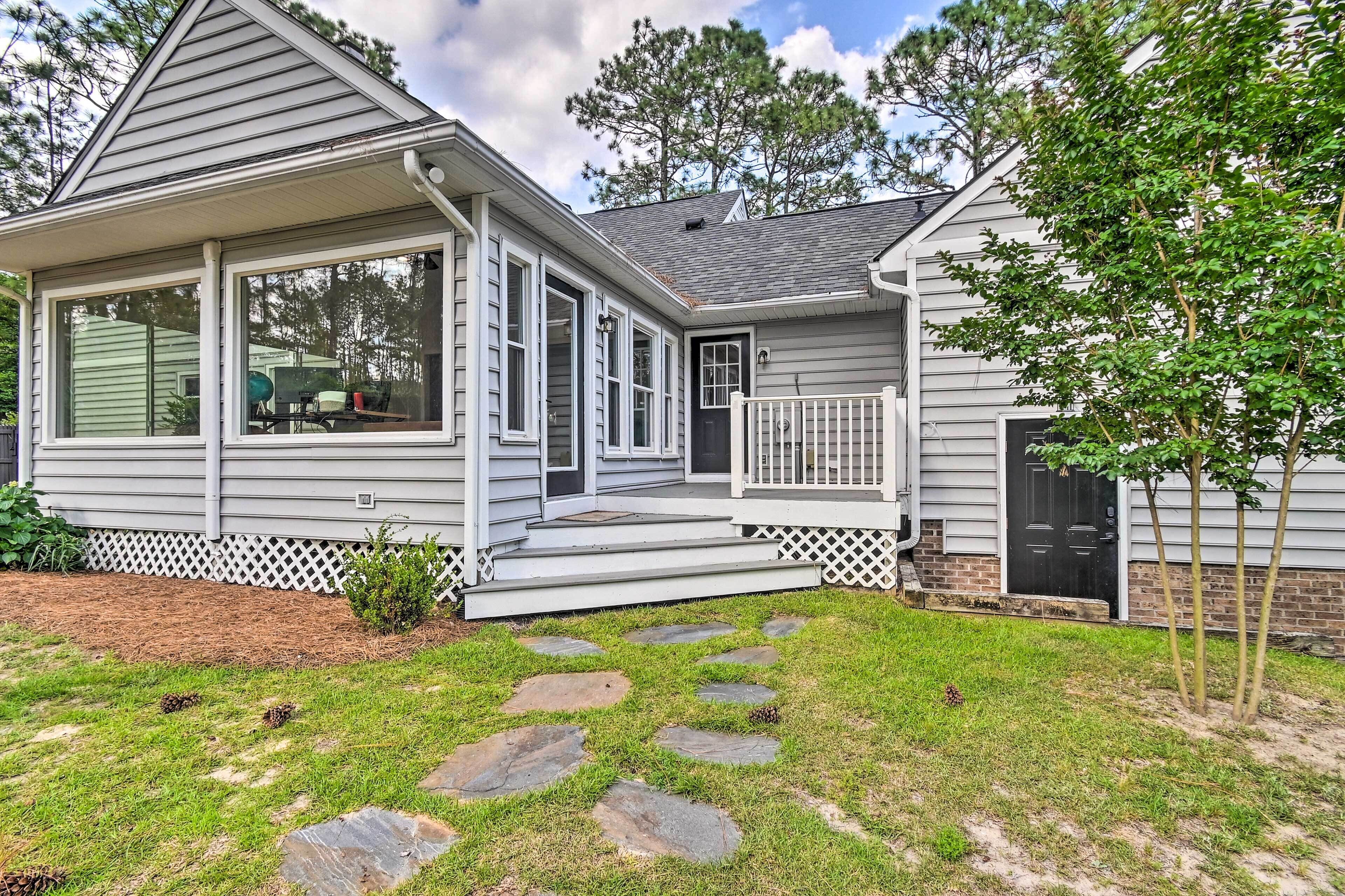 A single-story house with a covered porch, a front door, and a small front yard with stepping stones.