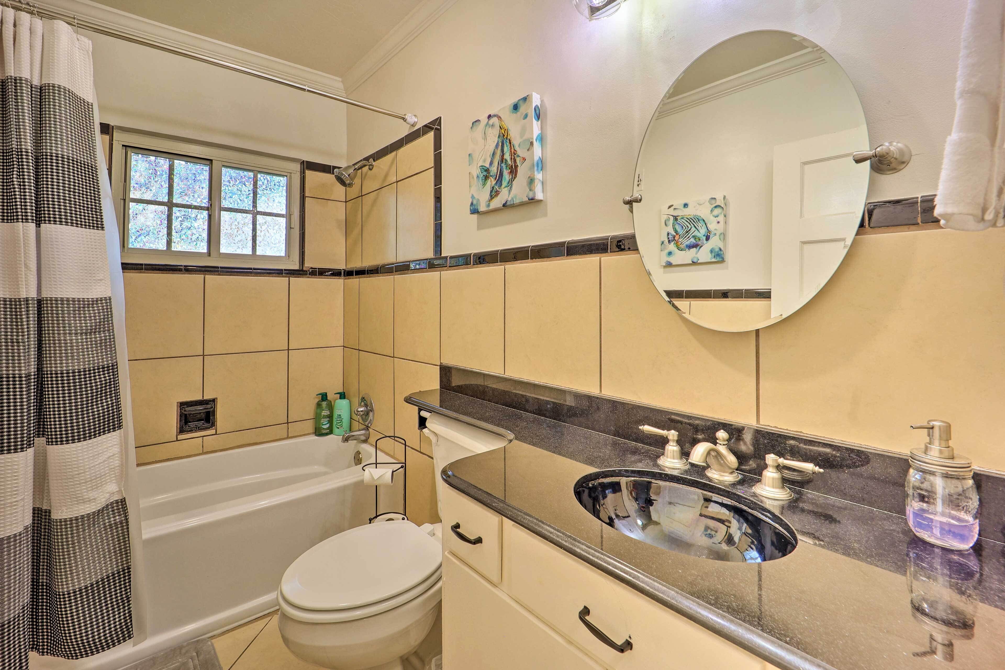 Une salle de bain avec une baignoire, des toilettes, un lavabo et une fenêtre.