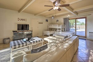 Un salon confortable avec un canapé, un téléviseur, un ventilateur de plafond et un lit superposé.
