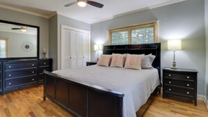 A bedroom with a large bed, a ceiling fan, a dresser, a nightstand, and a window with blinds. - 10 Mi to Grand Lake: Home w/ Game Room in Jay! (Jay)