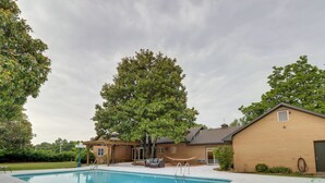A swimming pool with a hammock, a brick building, and a large tree. - 10 Mi to Grand Lake: Home w/ Game Room in Jay! (Jay)