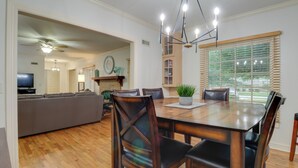 A dining area with a wooden table and chairs, a sofa, and a television in the background. - 10 Mi to Grand Lake: Home w/ Game Room in Jay! (Jay)