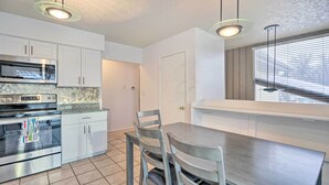 A modern kitchen with white cabinets, a built-in oven, and a dining area with a wooden table and chairs.