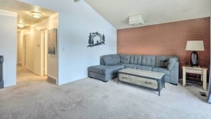 A living room with a sectional sofa, a coffee table, and a lamp on a side table.