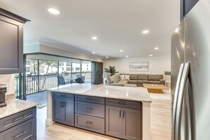 A modern kitchen with dark cabinets, a marble countertop, and a stainless steel refrigerator. - Luxury Sanibel Condo w/ Ocean View: Steps to Beach (Sanibel)