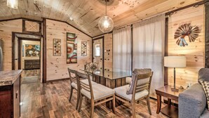 A wooden interior with a glass dining table, wooden chairs, a sofa, and a lamp. - Somerset Cabin, Close to Lake Access! (Somerset)