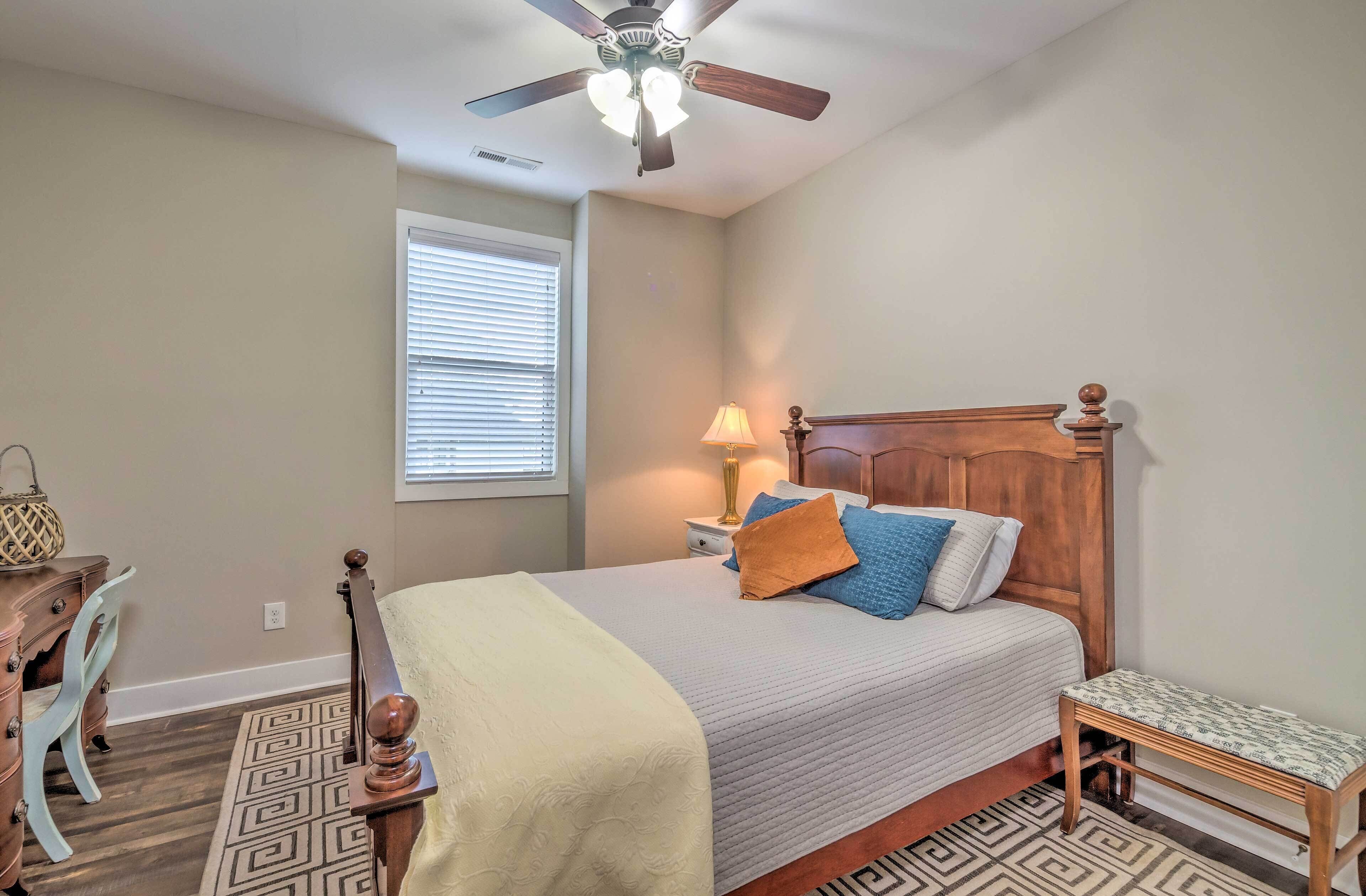 Une chambre à coucher avec un lit, une table de chevet, une lampe et un ventilateur de plafond.