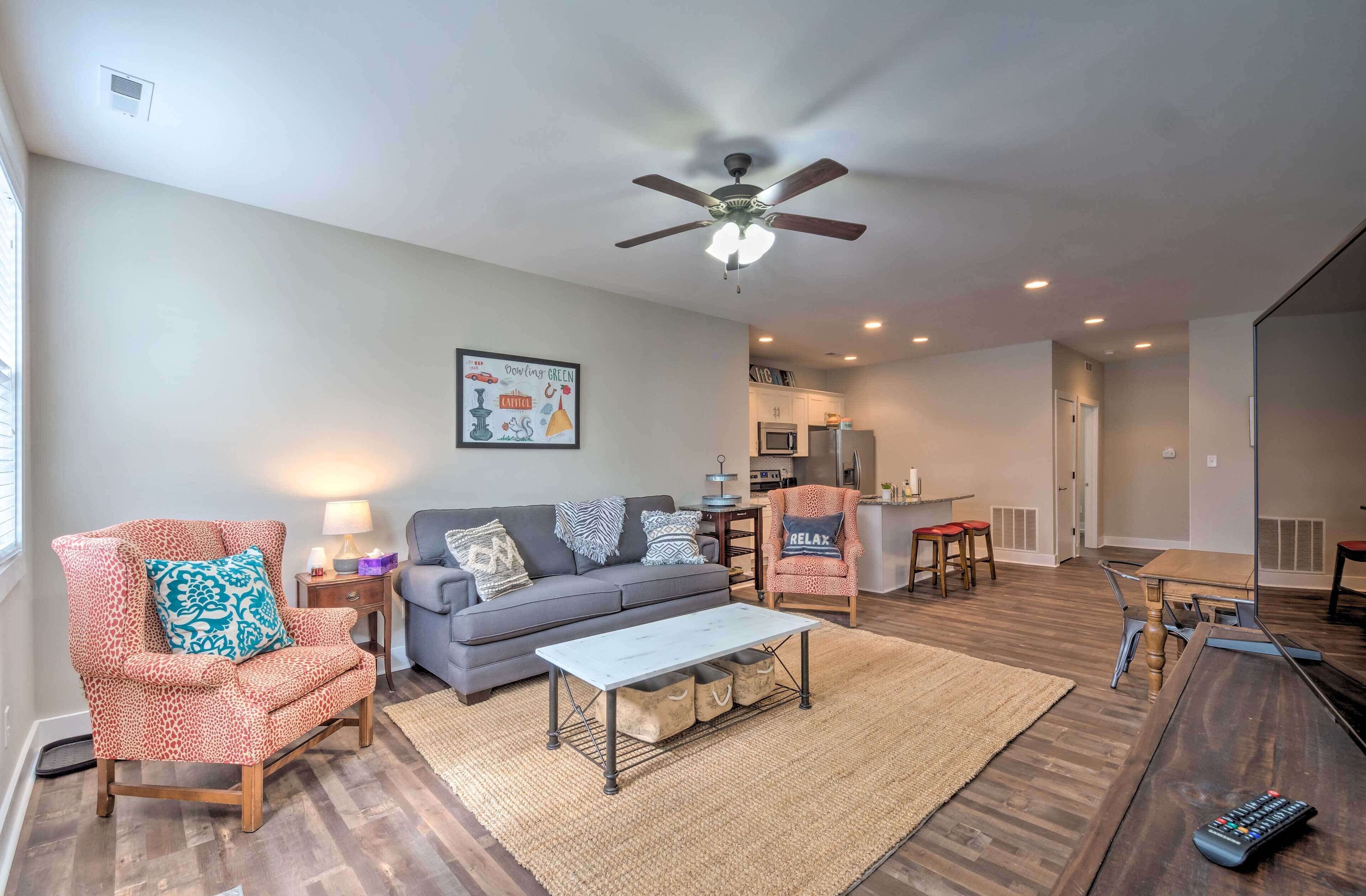 A living room with a sofa, armchair, coffee table, and a ceiling fan.