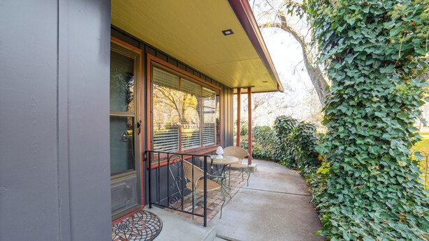 A covered outdoor seating area with a table and chairs, a door with glass panels, and a wall covered in ivy. - Couples Getaway in North End Boise - Walk to Dtwn (Boise)