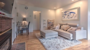 A modern living room with a grey sofa, a white rug, and a dining area with a table and chairs. - Couples Getaway in North End Boise - Walk to Dtwn (Boise)