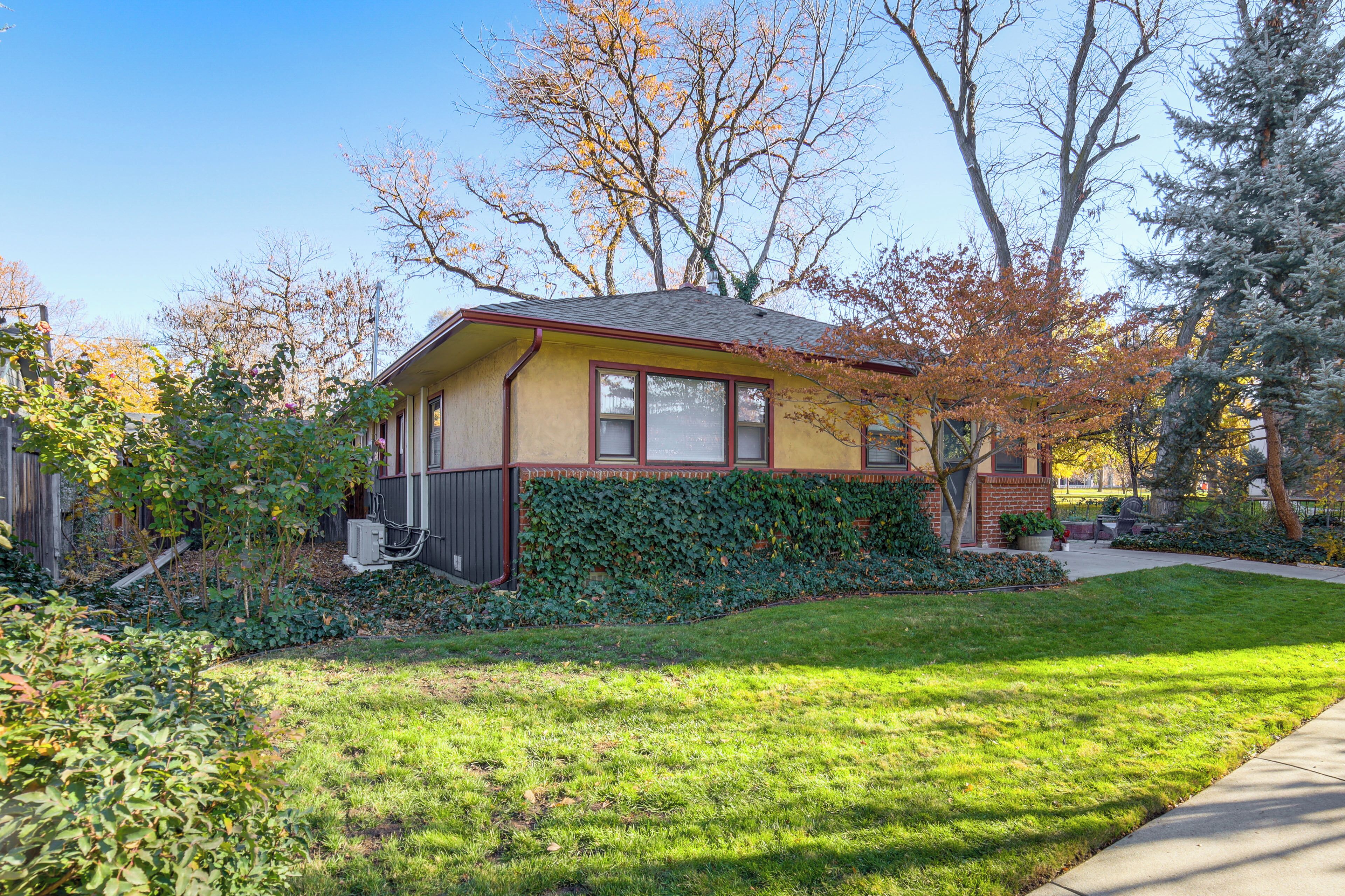 A single-story house with a sloped roof, a front porch, and a well-maintained front yard with grass and trees.