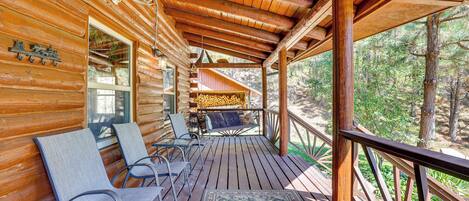Une cabane en bois dotée d’un porche couvert, de meubles d’extérieur et offrant une vue sur la forêt.