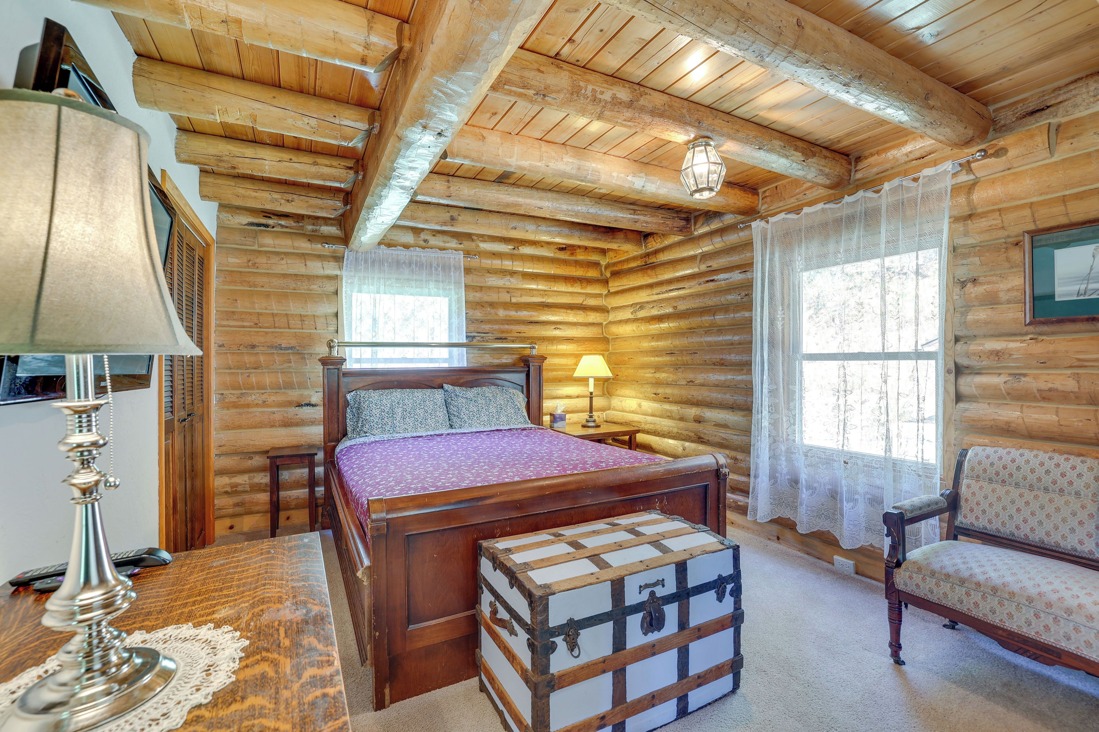 Ein Schlafzimmer in einer Holzhütte mit Bett, Nachttisch, Lampe und einer Kommode.