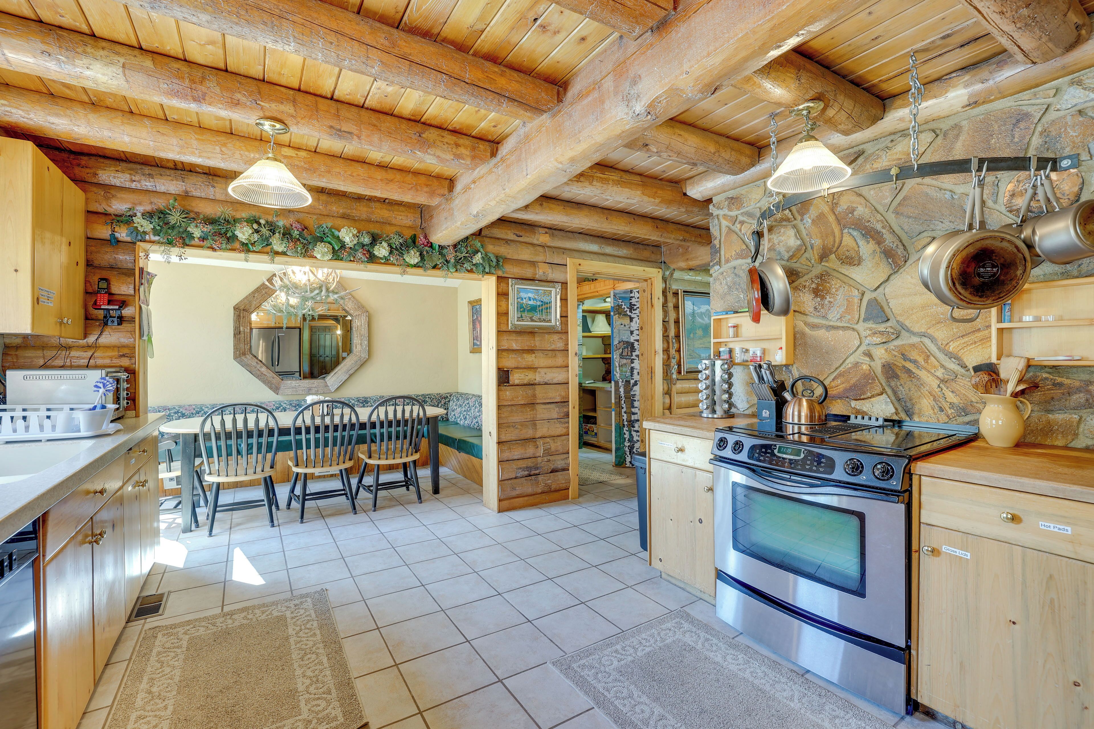 A rustic kitchen with wooden beams, a stone wall, and a large stove.