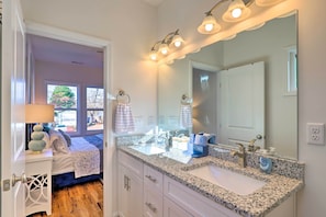 Une salle de bain dotée d’un comptoir en granit, d’un double lavabo et d’un grand miroir.