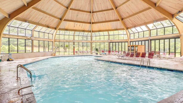 An indoor swimming pool with a wooden roof and large windows. - Cozy Camelback, Pocono Retreat w/ Mountain Views! (Tannersville)