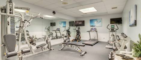 Un gimnasio con diversos equipos de ejercicio, incluyendo cintas de correr, bicicletas estáticas y máquinas de pesas.