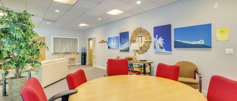 A conference room with a round table, red chairs, and a potted plant.
