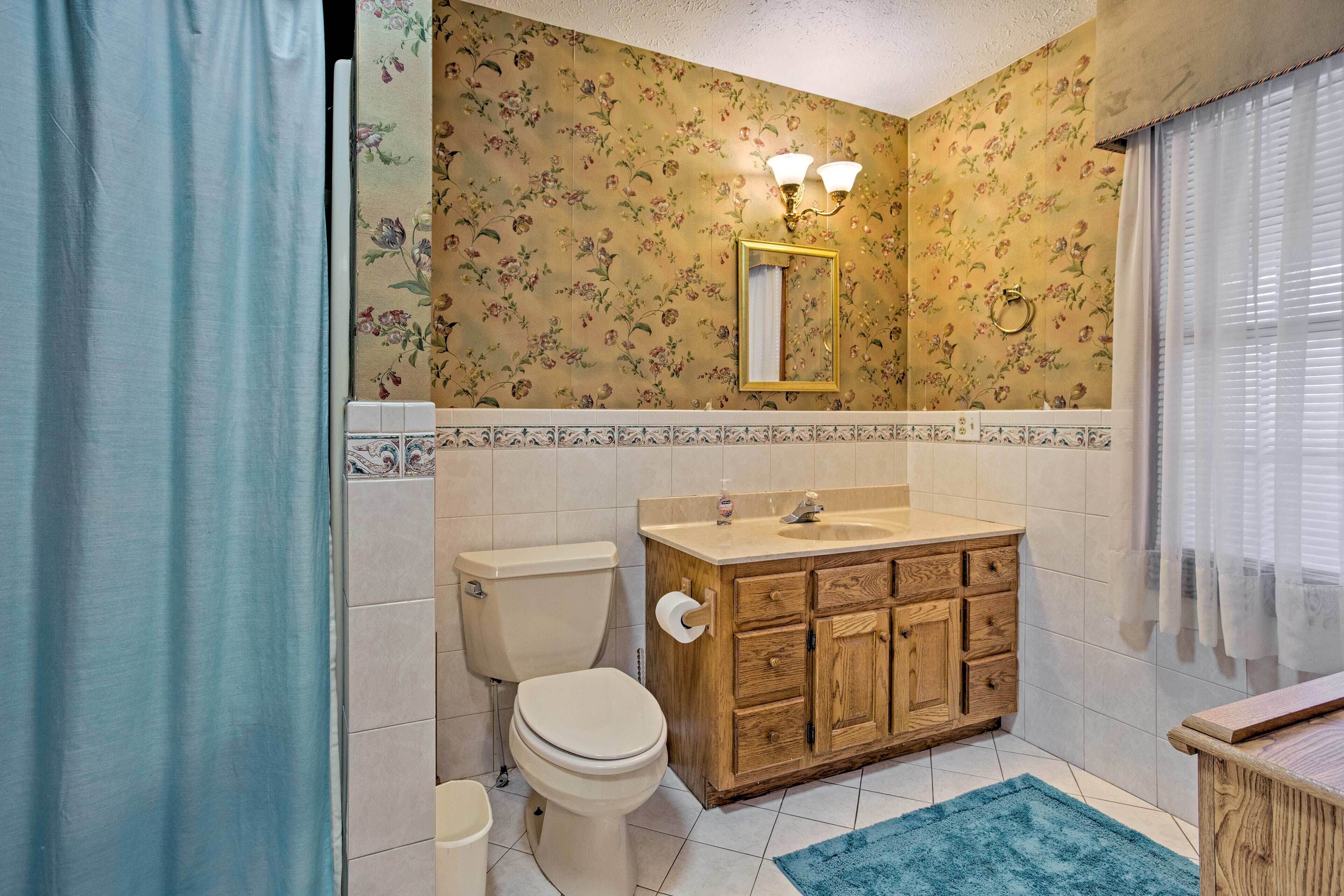 A bathroom with a toilet, sink, and wooden cabinet.