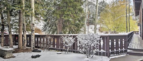 Un jardín cubierto de nieve con una valla de madera, árboles y un sendero pavimentado.