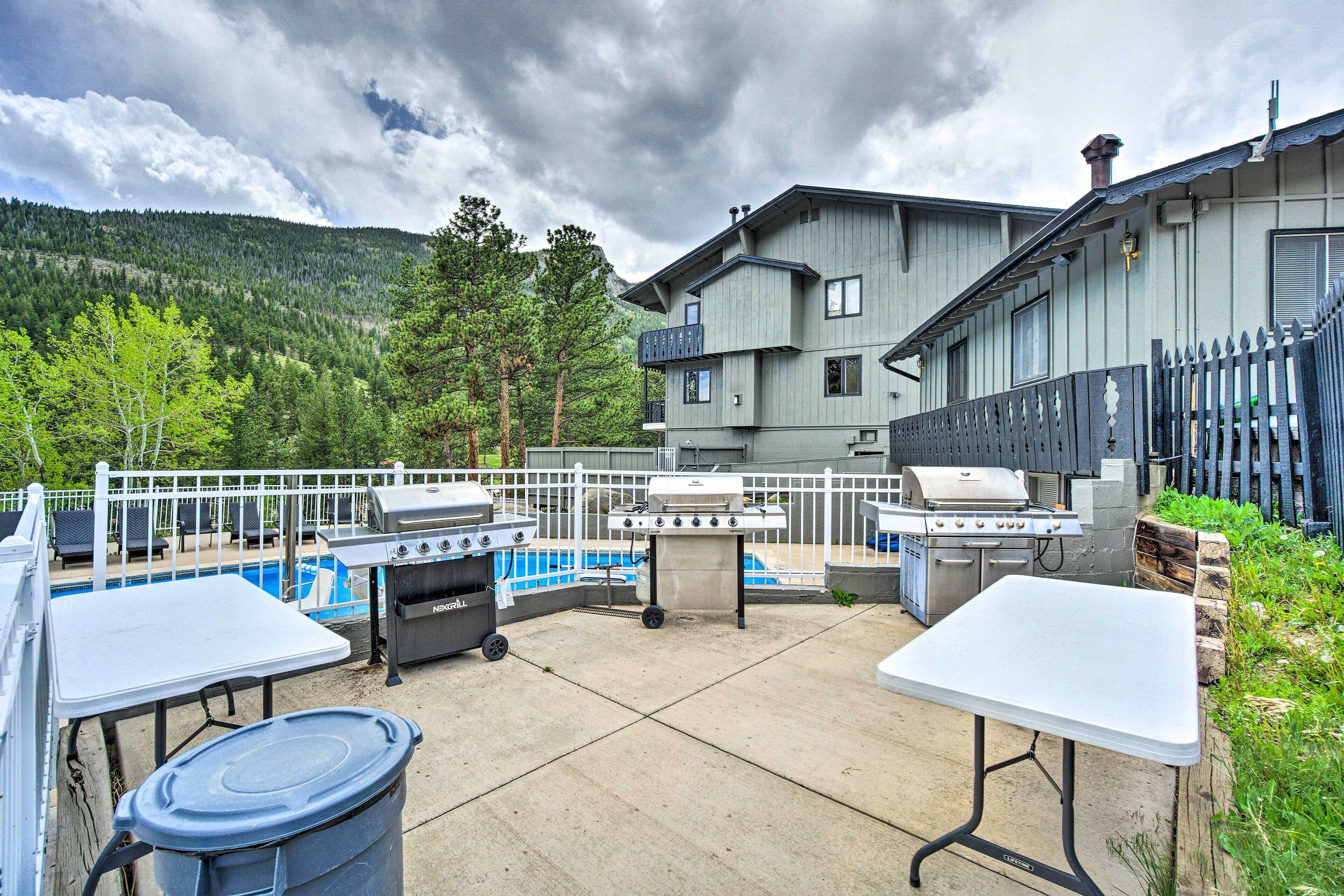 An outdoor patio with a pool, barbecue grills, and a table.
