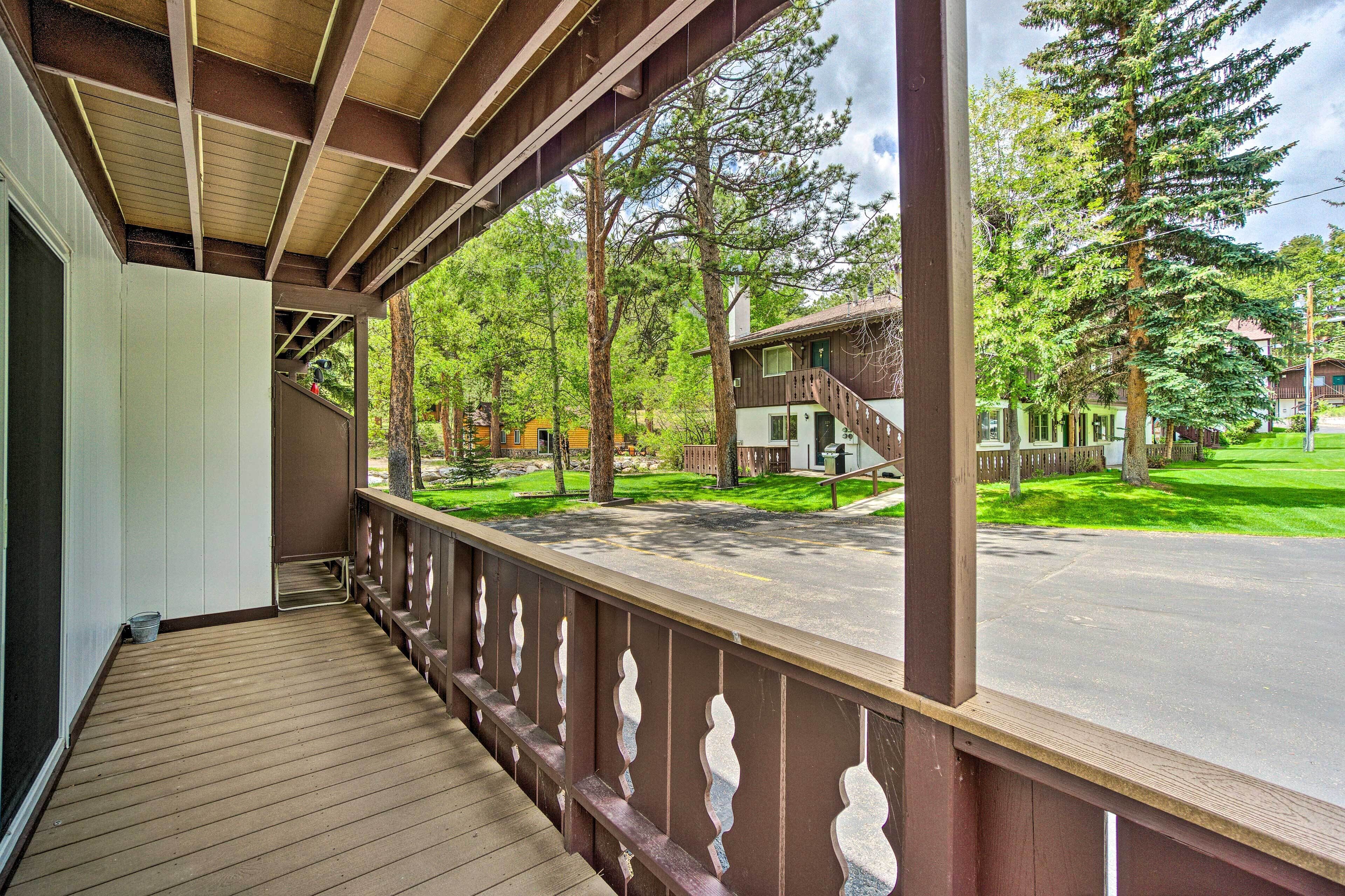 A wooden deck with a railing, overlooking a residential street with houses and trees.