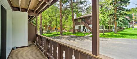 A wooden deck with a railing, overlooking a residential street with houses and trees.