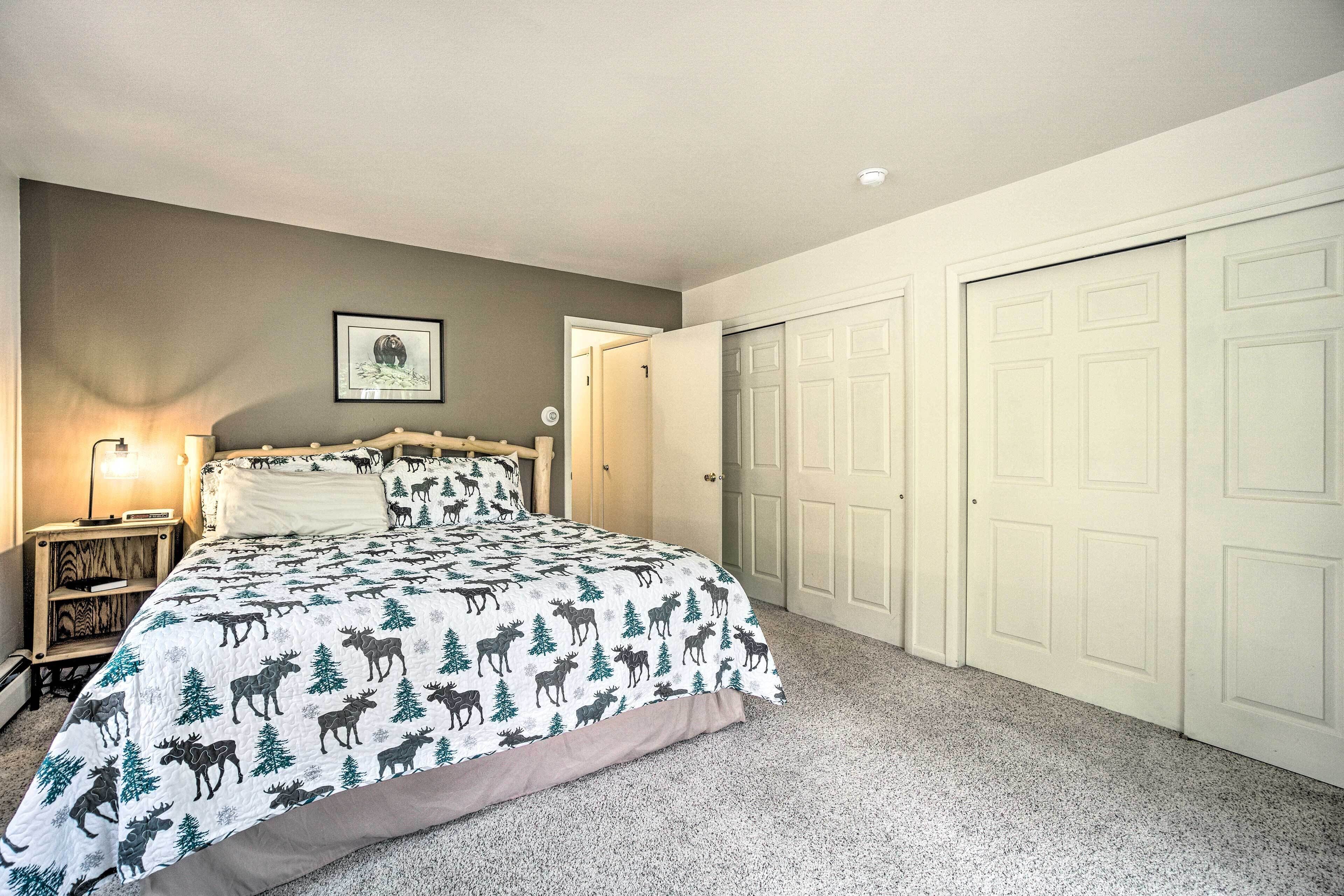 Un dormitorio con cama, mesita de noche, lámpara y puerta.