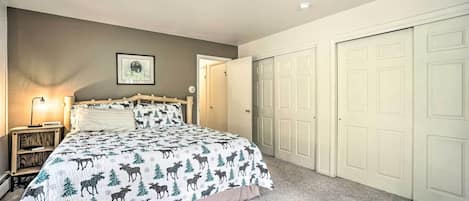 Un dormitorio con cama, mesita de noche, lámpara y puerta.
