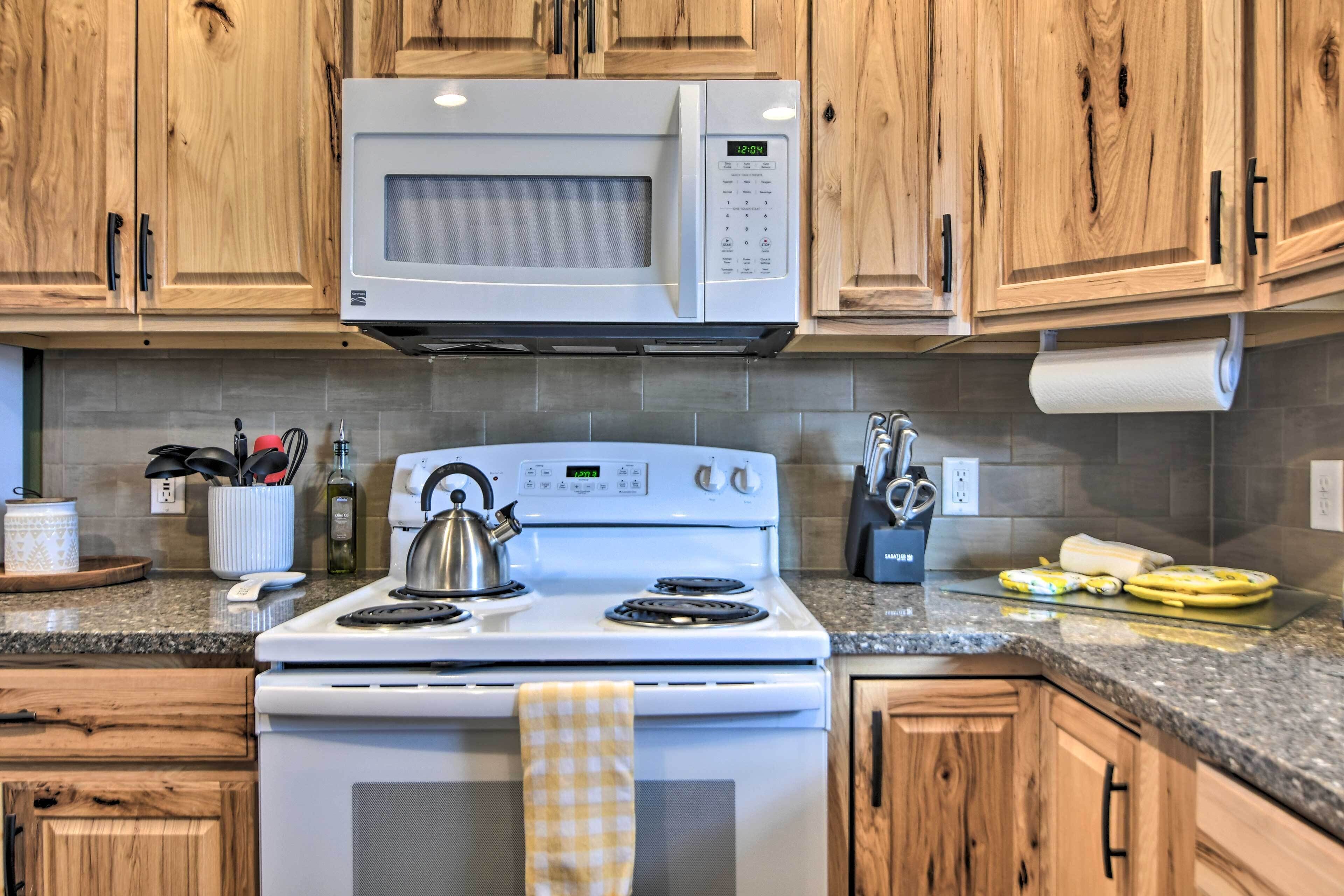A kitchen with wooden cabinets, a white stove, and a microwave.