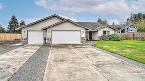 A single-story house with two attached garages, a front porch, and a well-maintained lawn. - Upscale Home w/ Indoor Sauna on Sunset Pond! (Ferndale)
