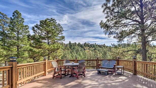 A wooden deck with a table and chairs, surrounded by trees. - Charming Ruidoso Home w/ Deck & Lovely Views! (Ruidoso)