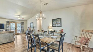 A dining area with a wooden table, chairs, and a chandelier. - Charming Ruidoso Home w/ Deck & Lovely Views! (Ruidoso)