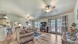 A spacious living room with a fireplace, a large sofa, and a television. - Charming Ruidoso Home w/ Deck & Lovely Views! (Ruidoso)