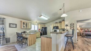 A spacious kitchen with wooden cabinets, a central island, and a dining area with chairs. - Charming Ruidoso Home w/ Deck & Lovely Views! (Ruidoso)