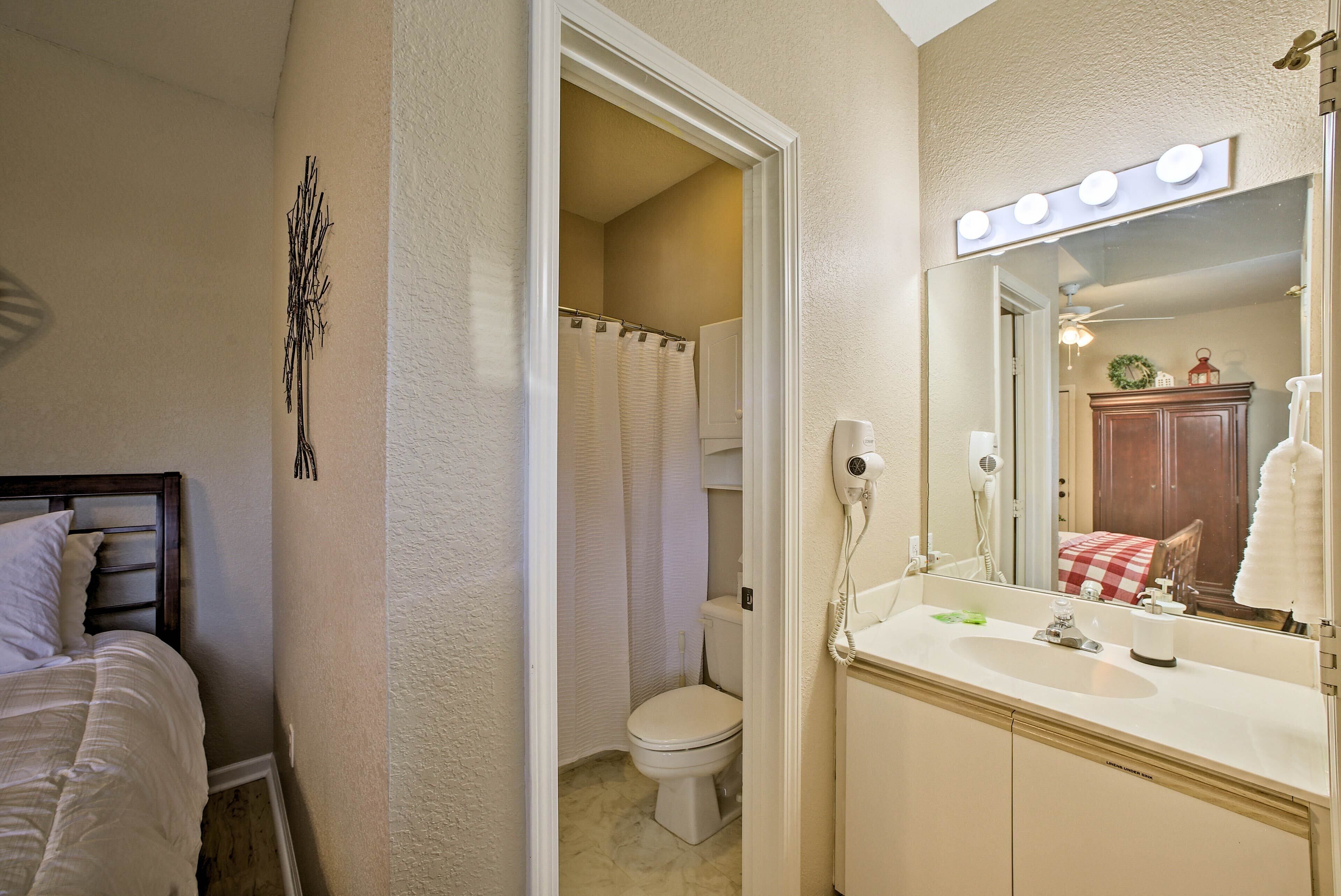 Een badkamer met een wastafel, een spiegel met verlichting, een toilet en een douchegordijn.