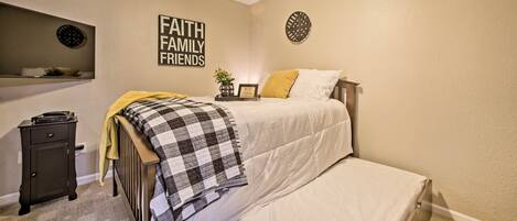 A bedroom with a bed, a nightstand, a ceiling fan, and a wall with a motivational quote.