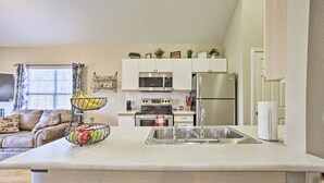 Une cuisine moderne dotée d’un îlot central, d’appareils électroménagers en acier inoxydable et d’un four encastré.