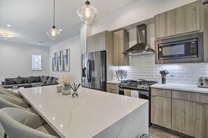 Une cuisine moderne dotée d’un grand îlot central, d’appareils électroménagers en acier inoxydable et de meubles de rangement en bois.