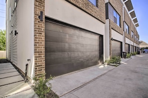 Un immeuble résidentiel moderne doté d’un grand portail de garage, d’une façade en briques et d’une allée pavée et bien entretenue.