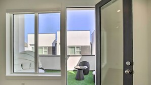 Ein modernes Zimmer mit einem großen Schiebeglastür, die zu einem Außenbereich mit künstlichem Rasen und Sitzgelegenheiten führt.