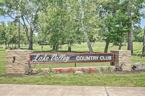 Naamplaatje voor Lake Valley Country Club, met een stenen voet en rode bloemen ervoor.