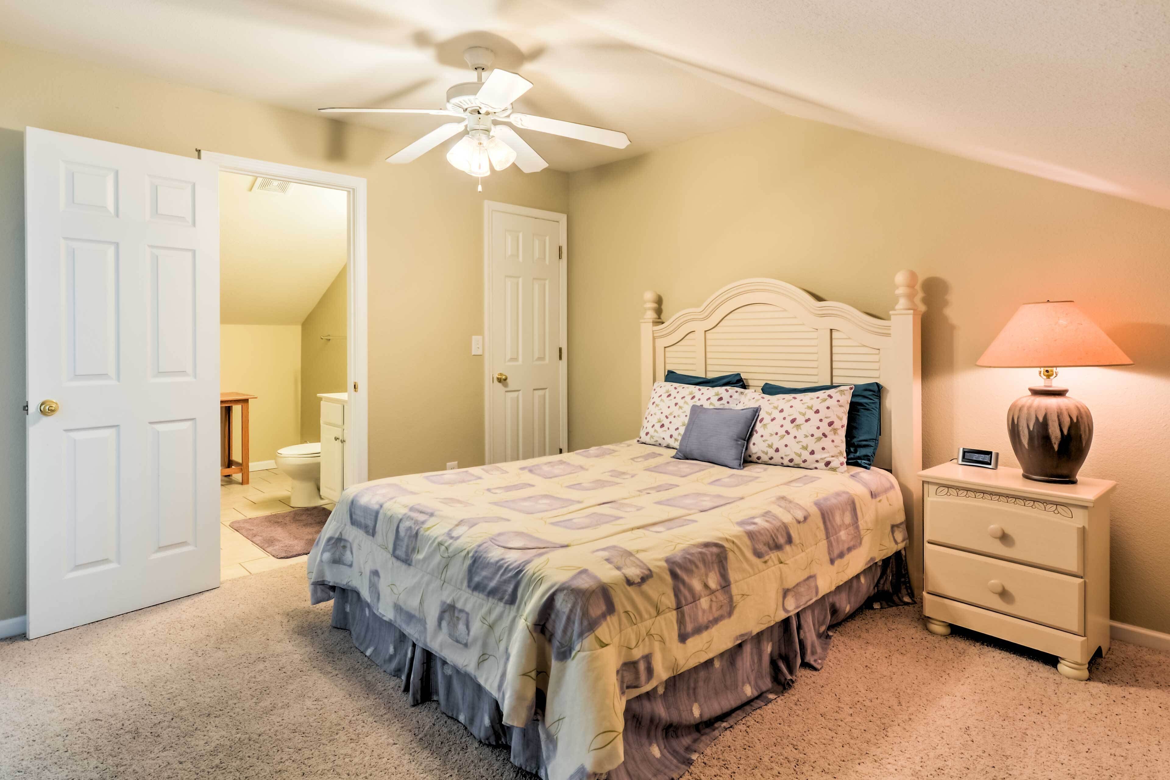 A bedroom with a bed, nightstand, lamp, and ceiling fan.