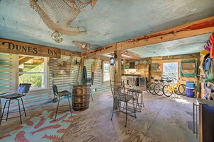 Un interior rústico con techo de madera, un cartel que dice "Dunes Inn" y un comedor con sillas de metal y una mesa de madera.