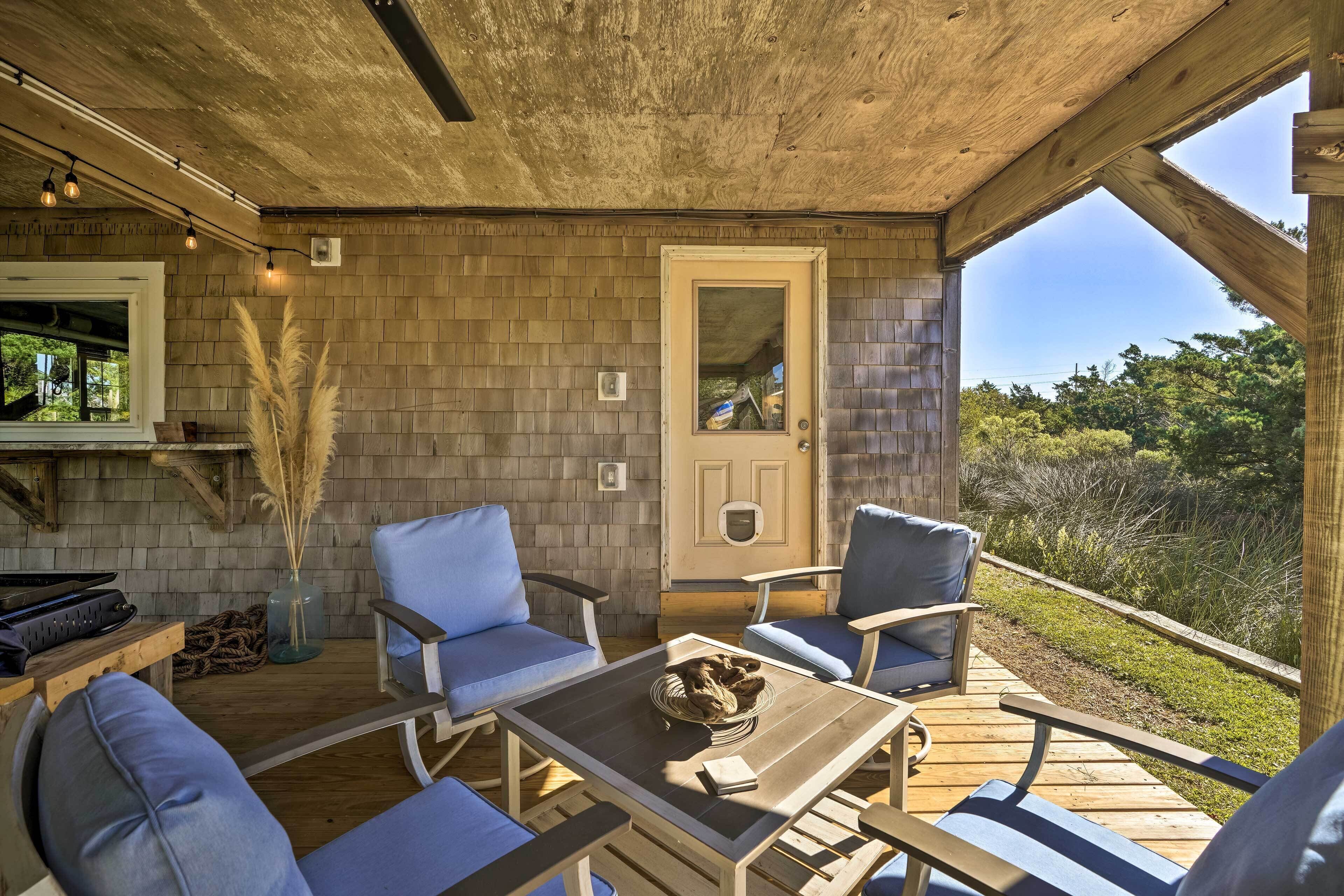 A covered outdoor seating area with wooden furniture and a view of the surrounding landscape.