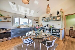 Una cocina moderna con una mesa redonda de vidrio, sillas blancas y armarios azules.